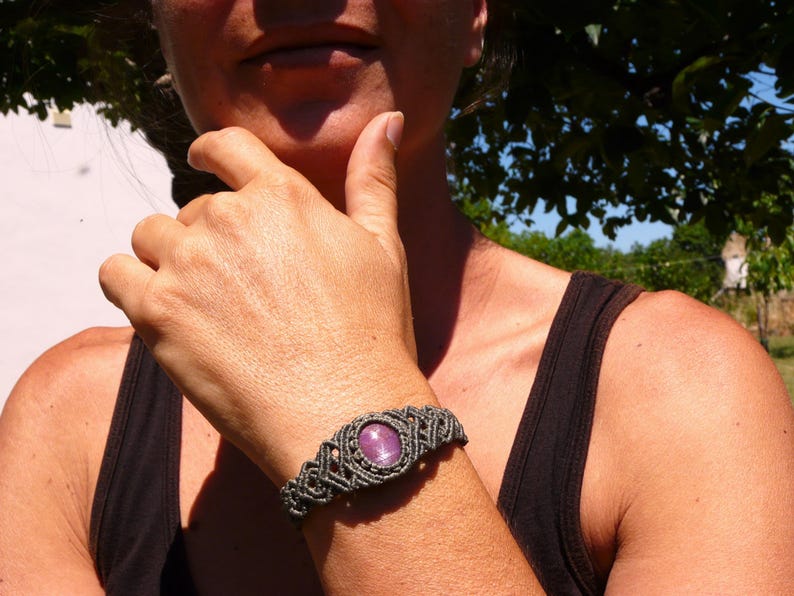 Bracciale a manetta intrecciato a mano in Macramè filato color grigio-verde con pietra naturale Rubino Stella, primo piano indossato da ragazza con canotta nera.