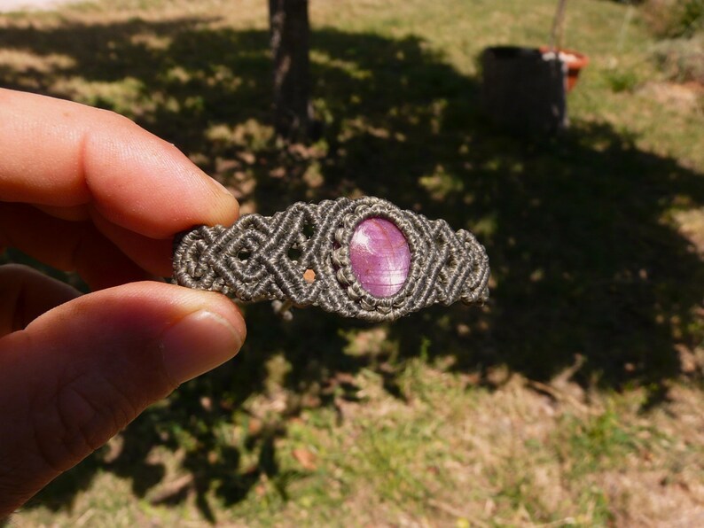 Bracciale a manetta intrecciato a mano in Macramè filato color grigio-verde con pietra naturale Rubino Stella vista lato sinistro primo piano su sfondo naturale