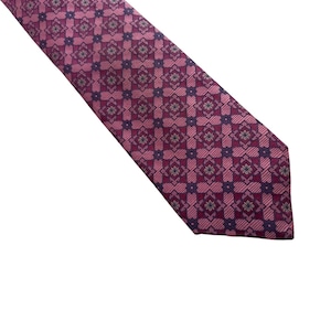 Peut inclure: Une cravate présentant un motif géométrique répétitif dans des tons magenta, violet foncé et rose clair. Le design se compose de carrés interconnectés et de petits motifs floraux, créant une texture visuelle structurée et symétrique.