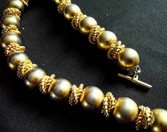 Può includere: Una collana in oro e argento con perline rotonde e una chiusura a scorrimento.