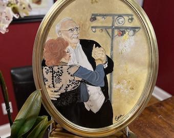 May include: Oval-shaped painting in a gold frame depicting an elderly couple dancing. The man wears a black suit and the woman has a red hairstyle and a black and white patterned top. The background is a light beige with gold accents.