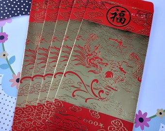 May include: A stack of red and gold Chinese New Year envelopes. The envelopes feature a dragon design and the Chinese character for "good fortune". The envelopes have the text "2000" on them.