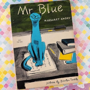 May include: A vintage book titled Mr Blue by Margaret Embry with illustrations by Brinton Turkle. The cover features a bright blue cat sitting on a desk with a pencil, notebooks, and a chalkboard background. The text 45 cents and TW 686 is visible.