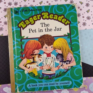 May include: A vintage Golden Book titled "Eager Reader: The Pet in the Jar". The cover features three children looking into a glass jar with a bug inside. The children are holding a puppy and a kitten.