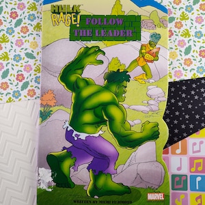 Może przedstawiać: Kolorowy komiks z Hulkiem w dynamicznej pozie, z tekstem "Hulk Rage! Follow the Leader." Ilustracja przedstawia Hulka w kolorze zielonym i fioletowym, na tle krajobrazu i innej postaci.