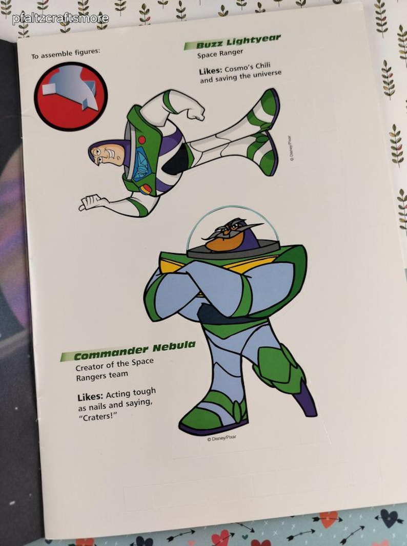 Peut inclure: Une page d'un livre d'activit&eacute;s pour enfants avec des illustrations de Buzz l'&Eacute;clair et du Commandant Nebula de Toy Story de Disney Pixar. Buzz l'&Eacute;clair est en position de vol, et le Commandant Nebula est debout, les bras crois&eacute;s. Le texte comprend les noms et les descriptions des personnages.