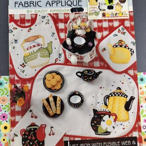 Könnte beinhalten: Ein Stoff-Applikations-Set mit verschiedenen Teekannen-Designs, einer Hasenfigur und Miniatur-Lebensmitteln. Das Set enthält den Text "No-Sew Fabric Applique" und Anweisungen zum Aufbügeln mit Vlies und zum Fertigstellen mit Glanzfarbe.