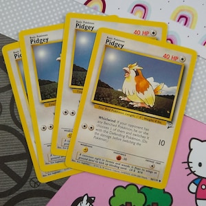 May include: Three yellow and white Pokemon trading cards featuring Pidgey, a small bird Pokemon with brown eyes and a yellow beak. The cards have a white background with a yellow border and feature the text "Basic Pokemon Pidgey" and "40 HP".