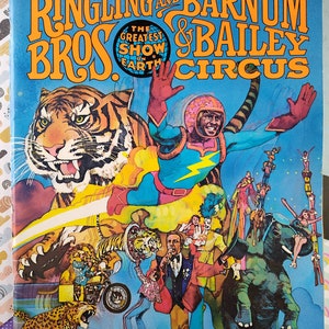 Peut inclure: Un programme et magazine vintage pour le cirque Ringling Bros. et Barnum & Bailey. La couverture présente une illustration colorée d'un tigre, d'un homme en costume bleu et jaune, et d'autres artistes de cirque. Le texte sur la couverture indique "The Greatest Show on Earth".