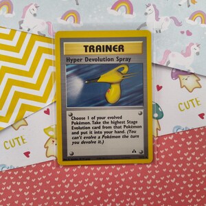 Può includere: Una carta Allenatore Pokémon gialla con il testo "Hyper Devolution Spray". La carta mostra uno spruzzino giallo e nero con un pulsante rosso. Il testo sulla carta recita: "Scegli 1 dei tuoi Pokémon evoluti. Prendi la carta Evoluzione di livello più alto di quel Pokémon e mettila nella tua mano. (Non puoi far evolvere un Pokémon nel turno in cui lo fai de-evolvere.)"