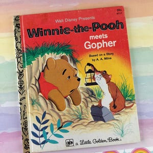 Könnte beinhalten: Ein Vintage "Winnie-the-Pooh meets Gopher" Little Golden Book. Das Cover zeigt Winnie the Pooh und Gopher, mit dem Text "Walt Disney Presents". Das Buch hat einen roten Hintergrund mit Illustrationen der Charaktere.