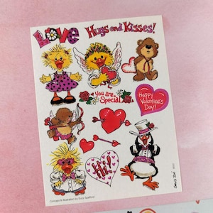 May include: A sheet of Valentine's Day stickers featuring cartoon animals and hearts. The stickers include ducks, a bear, and a penguin, with phrases like "Love," "Hugs and Kisses," and "Happy Valentine's Day!"