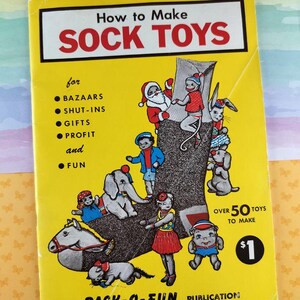 May include: A vintage yellow book titled "How to Make SOCK TOYS" with red text. The cover features illustrations of sock toys and characters. The book is a "PACK-O-FUN PUBLICATION" and costs £0.80.