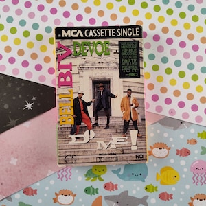 May include: A cassette tape single by Bell Biv DeVoe with the title "Do Me!" on a colorful polka dot background. The cassette tape cover features a photo of the group in front of a building. The text on the cassette tape cover reads "MCA Cassette Single Bell Biv DeVoe Do Me! Our music is mentally hip-hop smoothed out on the R&B tip with a pop feel appeal to it. -BBD"