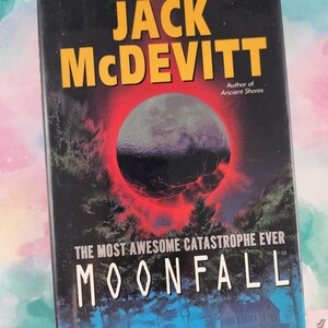 May include: A hardcover book titled Moonfall by Jack McDevitt. The black cover features a large, dark moon surrounded by a glowing red ring above a silhouette of trees and a house. The text reads: Jack McDevitt, Author of Ancient Shores, The Most Awesome Catastrophe Ever, Moonfall.