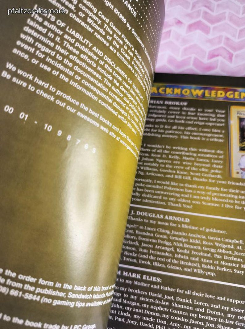 May include: Open book pages with text, including acknowledgements and copyright information. The pages have a yellowed appearance. The text includes names and thanks. The book is a guide for a trading card game.