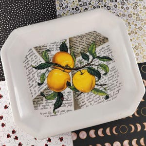 Puede incluir: Bandeja rectangular blanca con un diseño de tres manzanas amarillas sobre una rama con hojas verdes. La bandeja tiene una estética vintage con texto tipo guion en el fondo.
