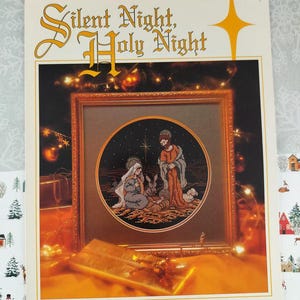 Puede incluir: Un patrón de punto de cruz enmarcado titulado "Silent Night, Holy Night". La obra de arte representa una escena de la natividad dentro de un marco circular. El diseño es de Cathy Livingston.