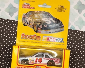 May include: A 1:64 scale die-cast replica of a NASCAR stock car. The car is white with red and blue accents and features the number 14 and the words "Windows 95" on the side. The car is packaged in a yellow box with the words "Racing Champions" and "NASCAR" on it.