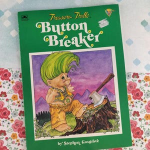 May include: A vintage children's book titled "Button Breaker" from the Treasure Trolls series. The cover is green with the title in white and yellow. The illustration features a troll with green hair and an axe. The author's name is Stephen Cosgrove.
