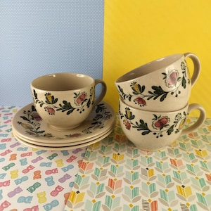 May include: Set of four vintage teacups and saucers with a floral pattern in shades of green, pink, and yellow. The cups and saucers are beige with a brown rim.