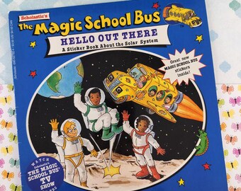 May include: A blue Scholastic book titled "The Magic School Bus: Hello Out There," featuring a yellow school bus transformed into a rocket ship. The cover shows astronauts and the Earth, with the text "A Sticker Book About the Solar System."