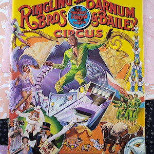 May include: A vintage program and magazine for the Ringling Bros. and Barnum & Bailey Circus. The cover features a colorful illustration of a clown, a performer on a motorcycle, and a group of acrobats. The text on the cover reads "The Greatest Show on Earth" and "112th Edition Souvenir Program & Magazine".