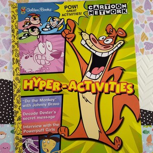 Puede incluir: Una portada de libro amarilla, naranja y verde con el título "Hyper-Activities" y el logotipo de Cartoon Network. La portada presenta una ardilla de dibujos animados con una gran sonrisa y una cola roja y naranja. El libro incluye actividades con personajes de los programas de Cartoon Network Johnny Bravo, Dexter's Laboratory y las Powerpuff Girls.