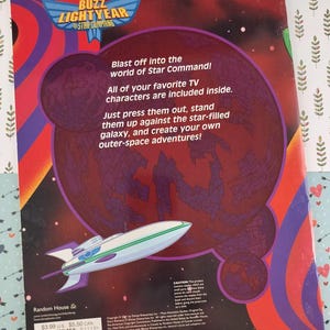 Peut inclure: Dos de livre Buzz Lightyear avec une illustration de vaisseau spatial. Le texte dit "D&eacute;collez vers le monde de Star Command !" et "Tous vos personnages TV pr&eacute;f&eacute;r&eacute;s sont inclus."