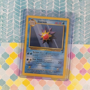 May include: A Starmie Pokémon trading card, featuring a blue and yellow design with a central image of a purple and red star-shaped creature. The card is 3' 7" long and weighs 176 lbs.