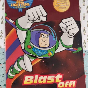 Op de afbeelding: Een Buzz Lightyear boekomslag met de titel "Buzz Lightyear of Star Command" en de woorden "Blast Off!" in geel en rood. De afbeelding toont Buzz Lightyear in een groen en wit ruimtepak, met zijn armen in een vuist. De cover zegt ook "Met uitdrukfiguren voor je eigen speelscènes!"