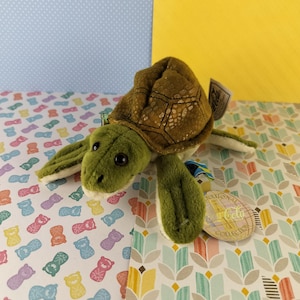 May include: A green and brown plush sea turtle toy with a National Geographic Kids Collection tag. The tag features a globe with the words "National Geographic Kids Collection" on it.