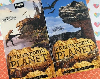 May include: Two VHS tapes of "Prehistoric Planet" from BBC Video, narrated by Ben Stiller. The covers feature dinosaur illustrations and the titles "Dino Dynasty I" and "Dino Dynasty II". The background is a colorful pattern.