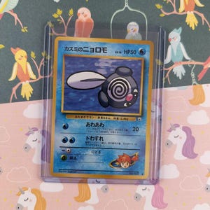 Könnte beinhalten: Eine Pokémon-Sammelkarte mit einem blau-schwarzen Charakter mit Spiraldesign. Die Karte befindet sich in einer Schutzhülle, vor einem Hintergrund aus Vögeln und Einhörnern.
