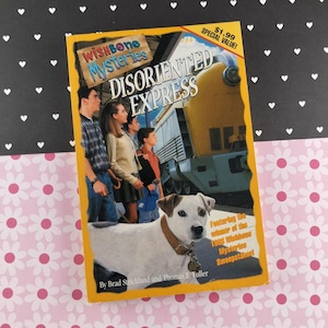 May include: A paperback book titled "Wishbone Mysteries: Disoriented Express" featuring a dog on the cover. The cover has a yellow border and shows a train and a group of people. The book is on a black and pink floral background.