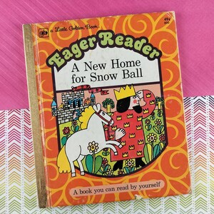 May include: Vintage "Eager Reader" children's book, "A New Home for Snow Ball." The cover features a white horse, a king, and a castle on an orange background with floral and swirl designs. The book is a "Little Golden Book."