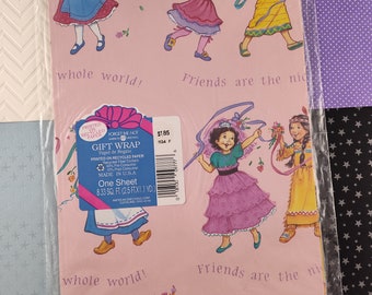 Puede incluir: Papel de regalo rosa con un patrón repetido de chicas con diferentes vestidos y el texto "Friends are the whole world!" impreso en él. El papel está hecho de papel reciclado y es una hoja, 0,77 metros cuadrados.
