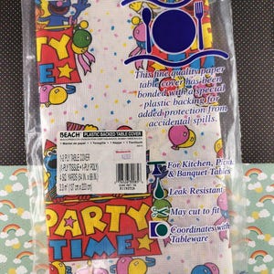 May include: A plastic-backed paper table cover in a clear plastic package. The cover features a colorful "Party Time" design with cartoon characters, balloons, and confetti. It measures 54 inches by 88 inches and is leak-resistant.