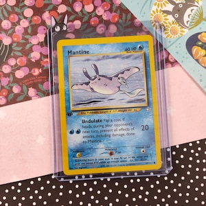May include: A blue and white Pokemon trading card featuring Mantine, a kite Pokemon. The card has a picture of Mantine swimming in the ocean. The card text reads "Undulate Flip a coin. If heads, during your opponent's next turn, prevent all effects of attacks, including damage, done to Mantine."