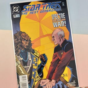 May include: A Star Trek The Next Generation comic book issue 74 titled Spectre of War. The cover features a Klingon character and Captain Jean-Luc Picard in a confrontation against a large yellow geometric background with blue and red accents.