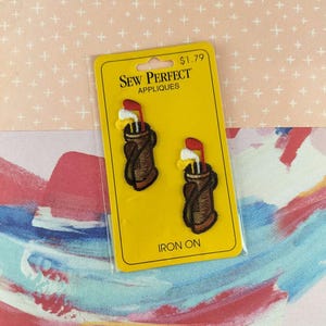 May include: Two iron-on golf club appliques on a yellow card. The appliques feature a brown golf bag with golf clubs. The card has the text "SEW PERFECT APPLIQUES" and "IRON ON".