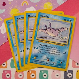 May include: A yellow and blue Pokemon card featuring Mantine, a kite Pokemon. The card has a blue and white illustration of Mantine swimming in the ocean. The card text reads "Undulate Flip a coin. If heads, during your opponent's next turn, prevent all effects of attacks, including damage, done to Mantine."