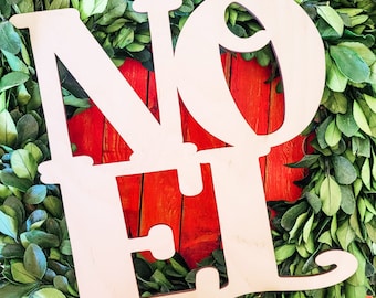 Può includere: Lettere in legno bianco che compongono la parola "NOEL" sono visualizzate su uno sfondo rosso. Le lettere sono circondate da una ghirlanda di bosso verde.