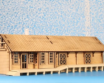 May include: A wooden model train station kit with a brown roof, beige walls, and a platform. The station has six windows and two doors. The kit is ready to be assembled.