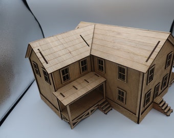 May include: A detailed wooden model of a two-story house with a porch and stairs. The model is made of light brown wood, with visible window frames and roof details. The house has a classic architectural design.
