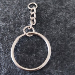 May include: A silver key chain with a round metal ring and a silver chain.