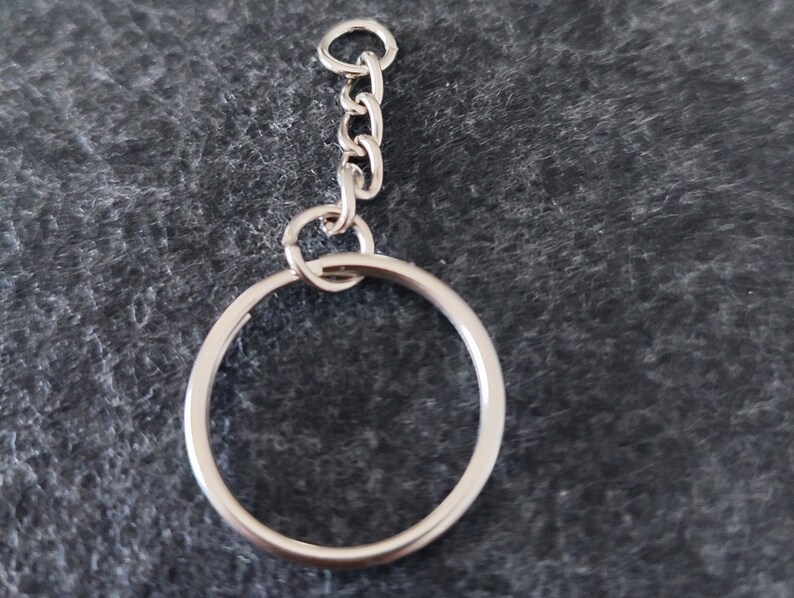 May include: A silver key chain with a round metal ring and a silver chain.