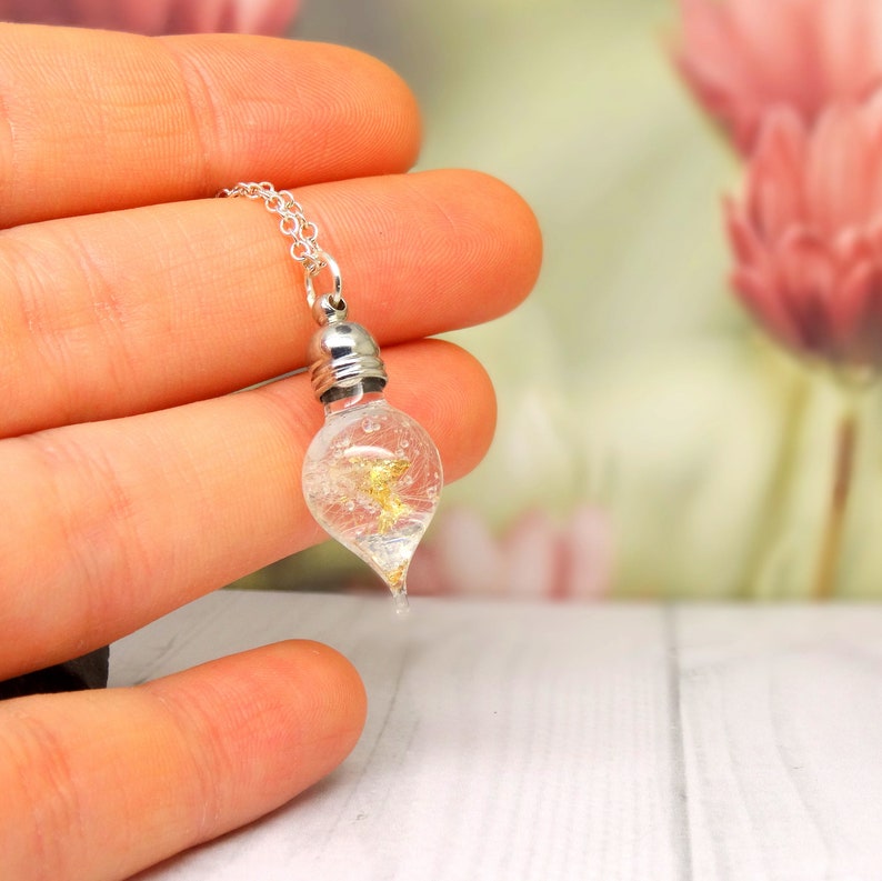 May include: A silver chain necklace with a clear glass teardrop pendant filled with gold flakes.