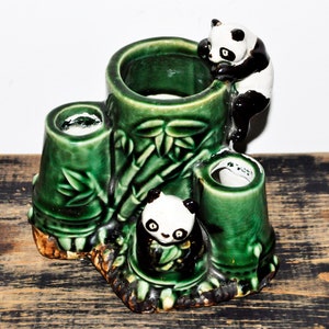Puede incluir: Un porta lápices de cerámica verde con forma de bosque de bambú con tres osos panda. Los osos panda están trepando por los tallos de bambú.