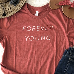 May include: A red t-shirt with the text "FOREVER YOUNG" printed in white on the front.